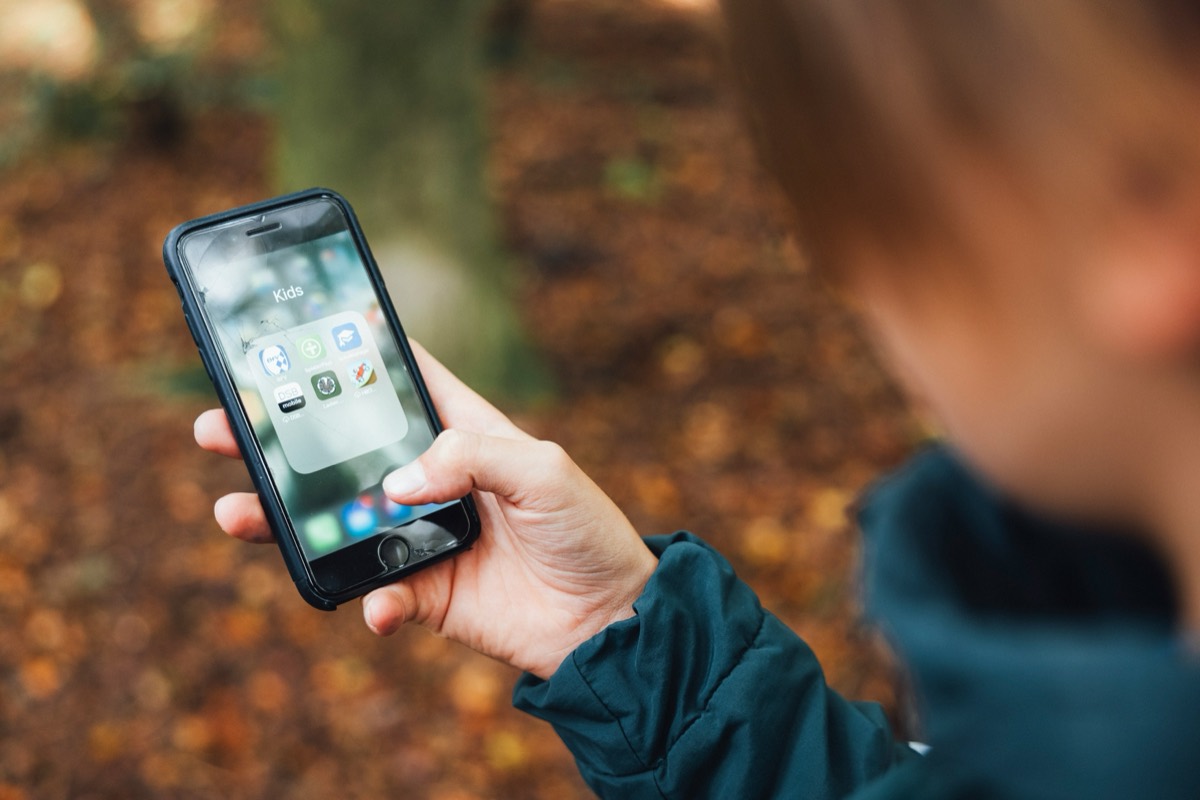 A person holding a smartphone outdoors.